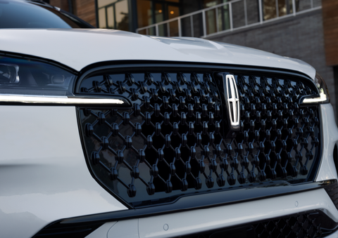 The black grille of a white 2025 Lincoln Aviator® SUV is shown with its fog lights on. | Hooks Lincoln in Fort Worth TX