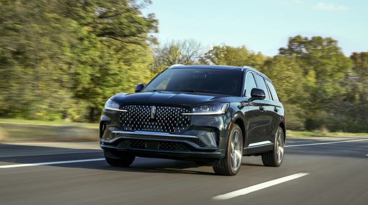 A 2025 Lincoln Black Label Aviator® SUV is being driven down a road lined with trees. | Hooks Lincoln in Fort Worth TX