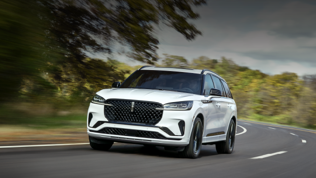 A white 2025 Lincoln Aviator® SUV is being driven down a road lined with trees. | Hooks Lincoln in Fort Worth TX