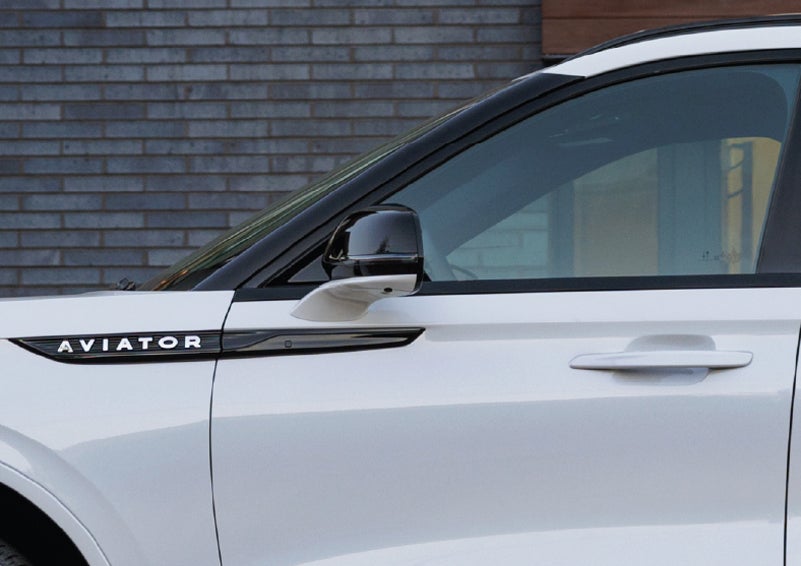 The driver’s side door and fender badging of a white 2026 Lincoln Aviator® SUV are showcased. | Hooks Lincoln in Fort Worth TX