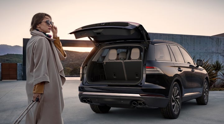 A woman approaches a 2026 Lincoln Aviator® SUV with its rear liftgate open. | Hooks Lincoln in Fort Worth TX