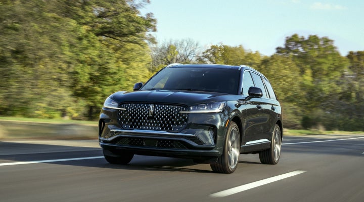 A 2026 Lincoln Black Label™ Aviator® SUV is being driven down a road lined with trees. | Hooks Lincoln in Fort Worth TX