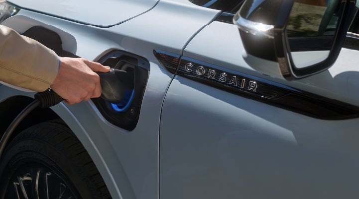 A hand is plugging in a 2026 Lincoln Corsair® Grand Touring Plug-in Hybrid SUV. | Hooks Lincoln in Fort Worth TX
