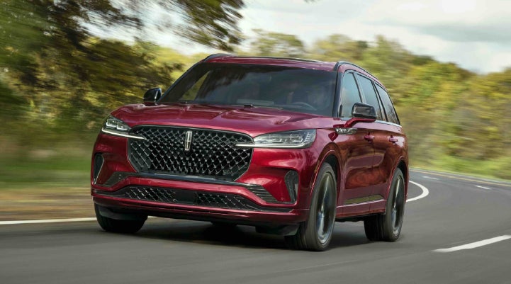 A 2027 Lincoln Aviator® SUV is being driven on a country road | Hooks Lincoln in Fort Worth TX