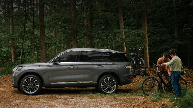A father and son load e-bikes on a bike rack attached to a 2027 Lincoln Aviator® SUV. | Hooks Lincoln in Fort Worth TX