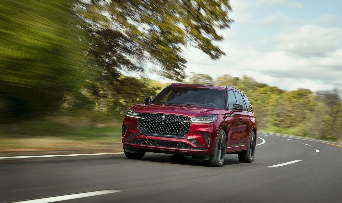 Red Lincoln Aviator driving on a tree lined road for Fort Worth TX families